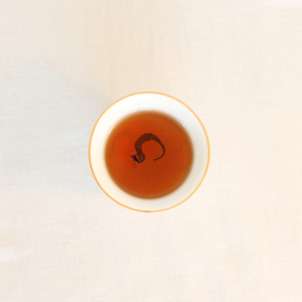 Brewed Rare Red Oolong Himalayan tea, rich amber liquor in a white ceramic cup