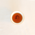 Brewed Rare Red Oolong Himalayan tea, rich amber liquor in a white ceramic cup
