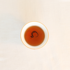 Brewed Rare Red Oolong Himalayan tea, rich amber liquor in a white ceramic cup