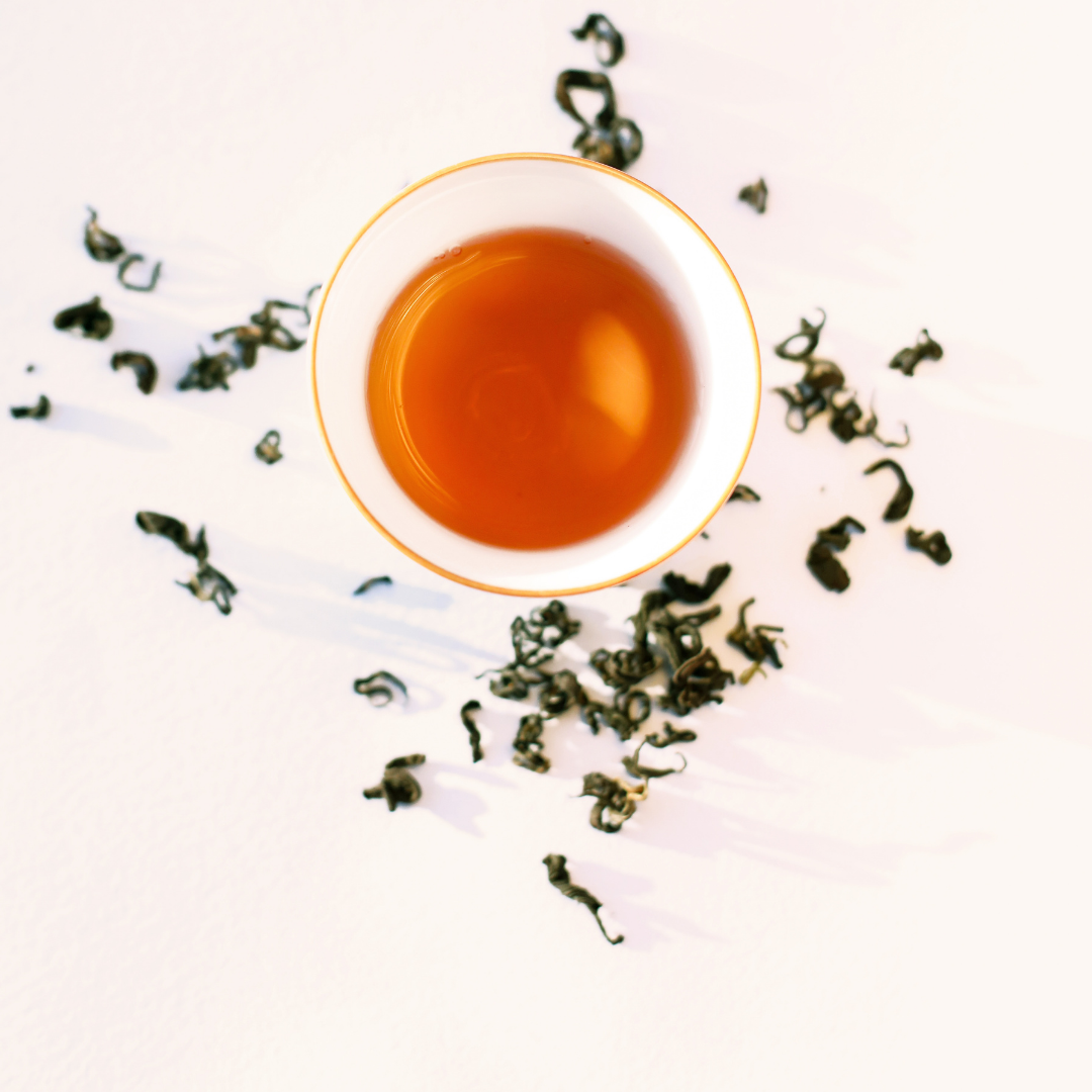 Rare Red Oolong Himalayan oolong, brewed cup surrounded by loose dry leaves