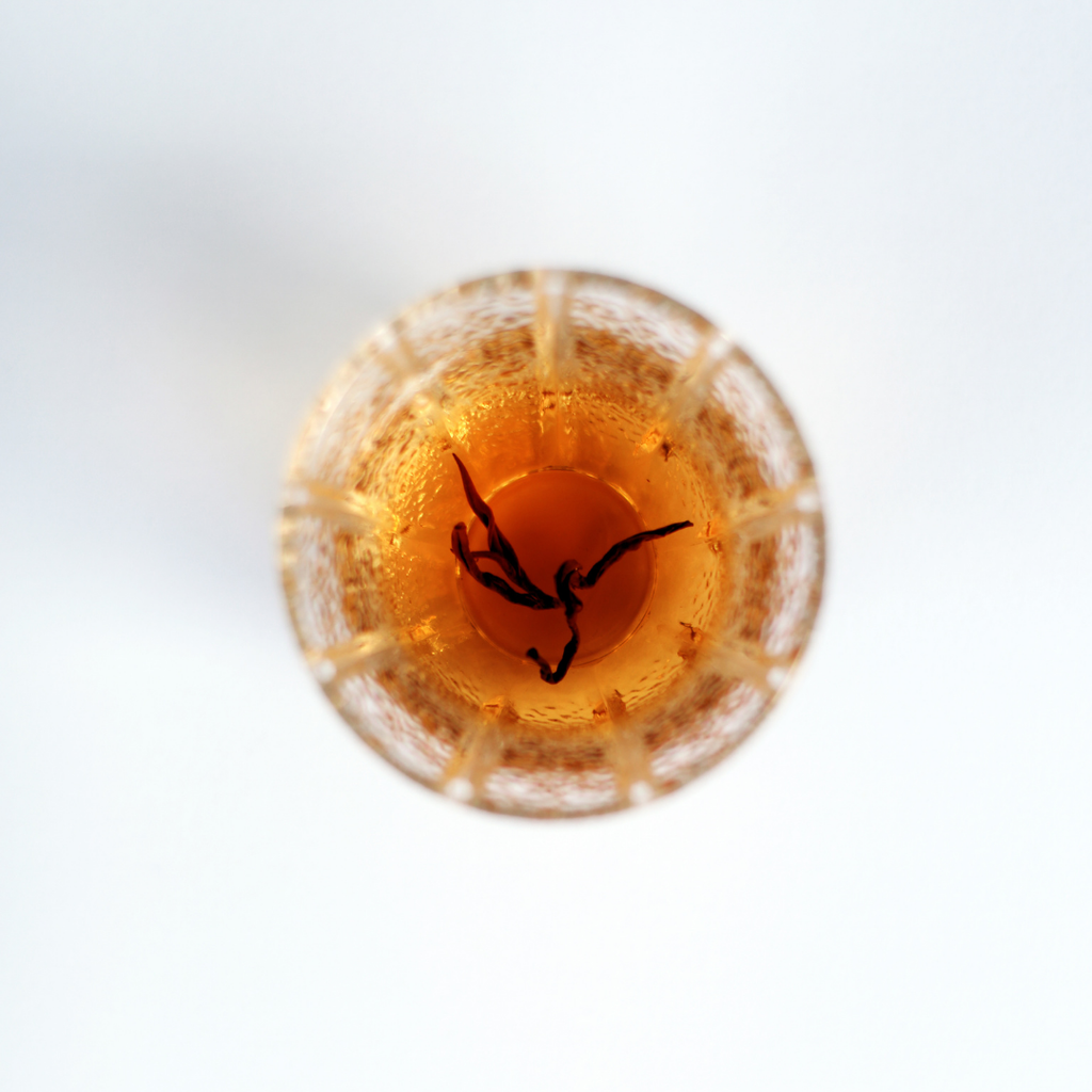 Close-up of brewed Rare Red Oolong tea, amber liquor in a glass tea cup