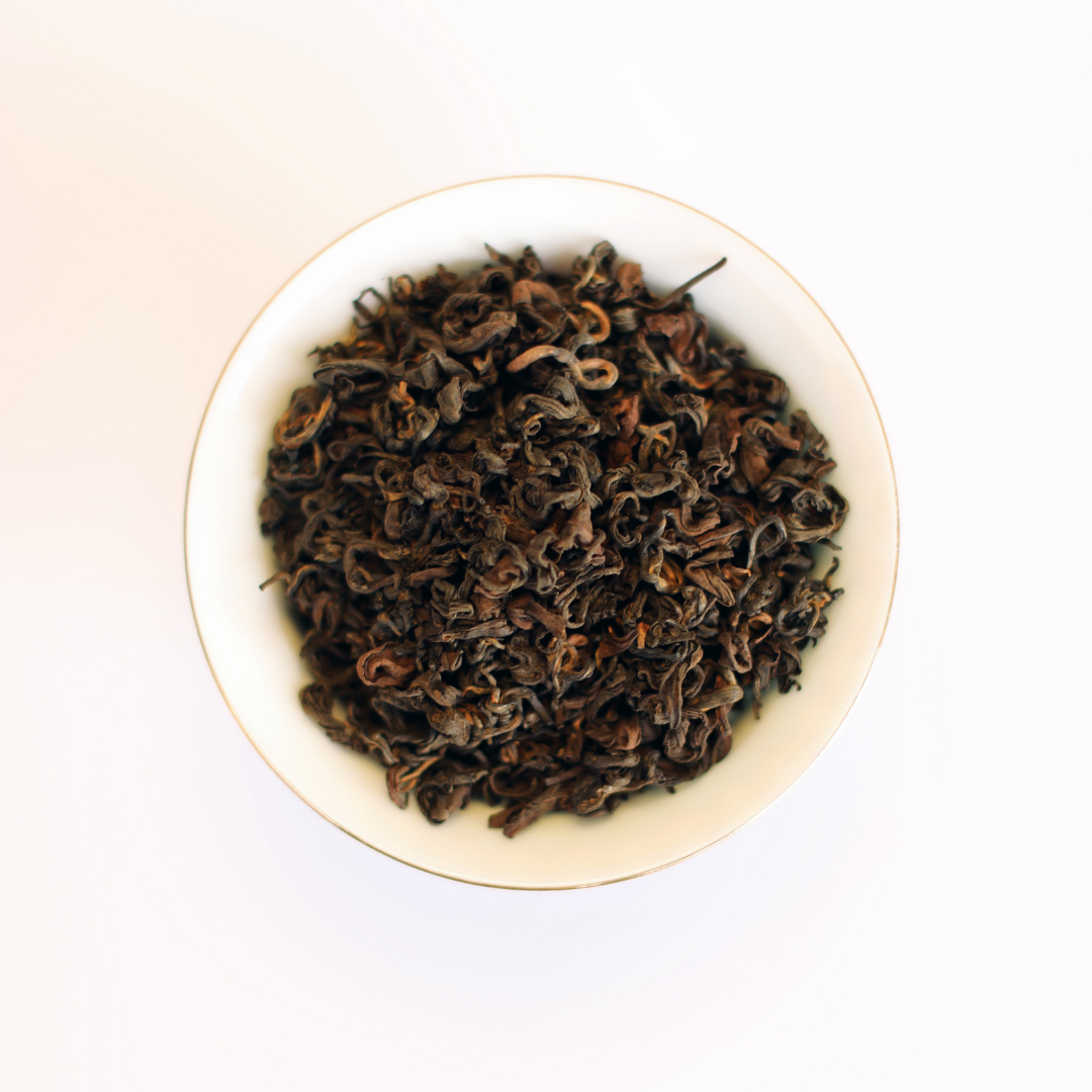 Dry whole leaves of Rare Red Oolong Himalayan oolong in a white bowl