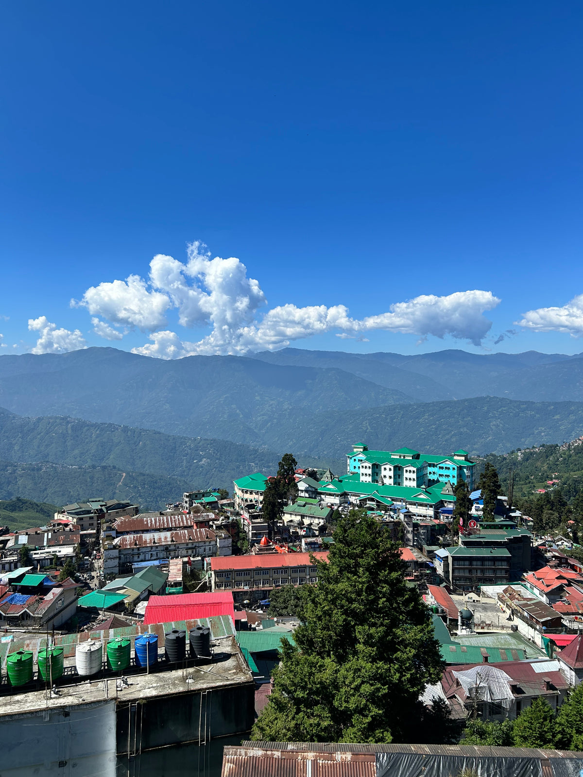 Darjeeling with green and red roofs by a lake under a clear blue sky