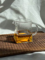 Himalayan Beauty oolong brewed in a glass pitcher on a wooden board: a bright amber, bug-bitten second flush from Darjeeling with muskmelon sweetness and a creamy finish.
