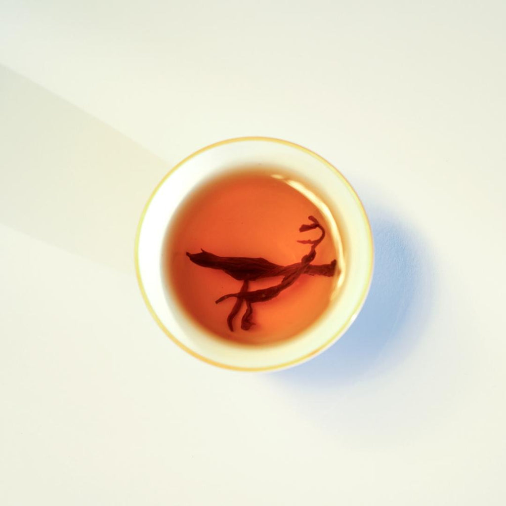 Brewed Himalayan Golden Black tea, warm amber liquor in a white ceramic cup.