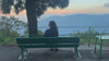 Swikriti, founder of Himali Cup, sitting on a bench overlooking the Himalayan hills at sunset
