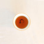 Brewed Rare Red Oolong Himalayan tea, rich amber liquor in a white ceramic cup