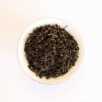 Dry whole leaves of Rare Red Oolong in a white bowl
